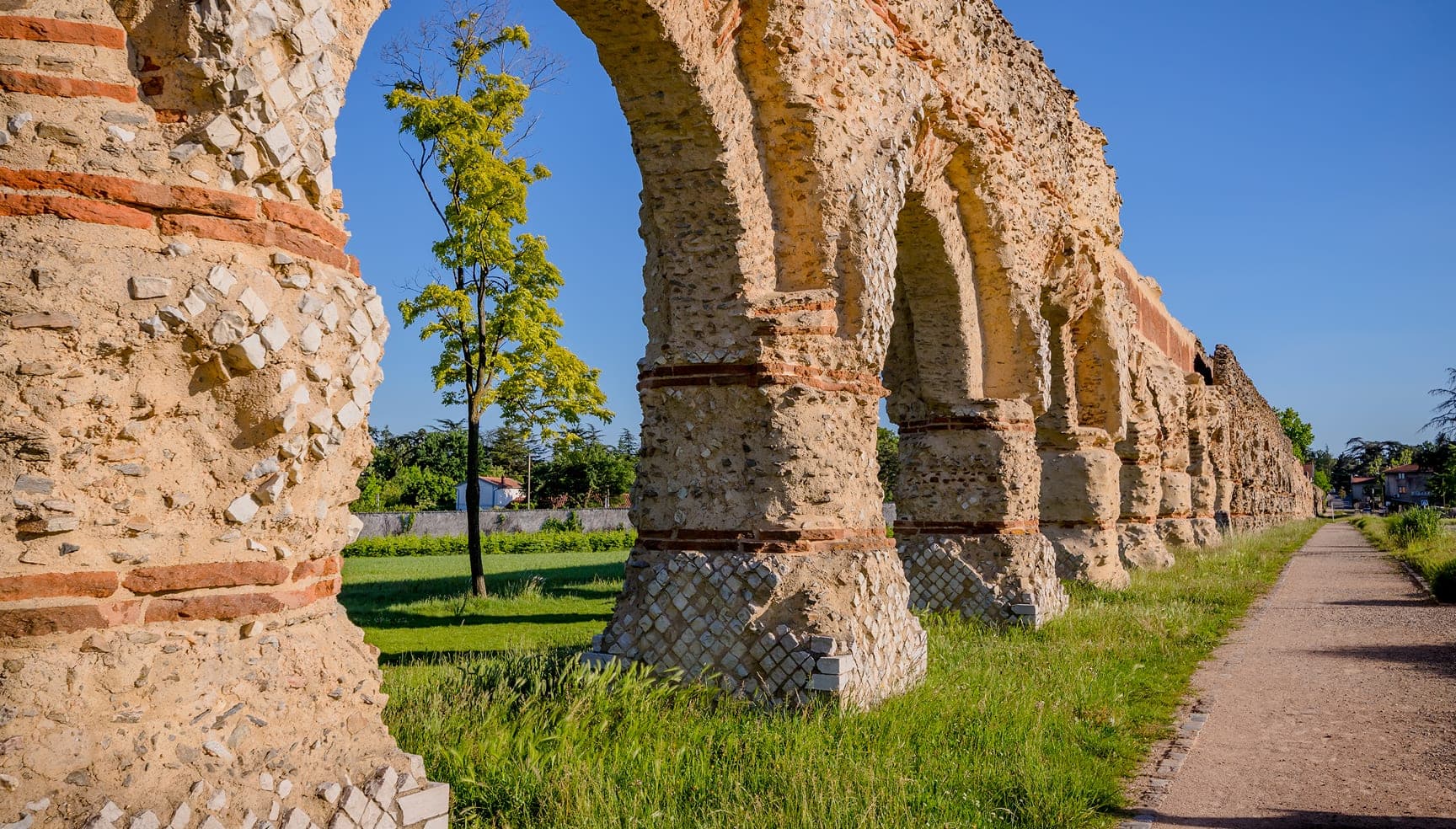 L’aqueduc romain de Chaponost au soleil, bordé d’un chemin de promenade